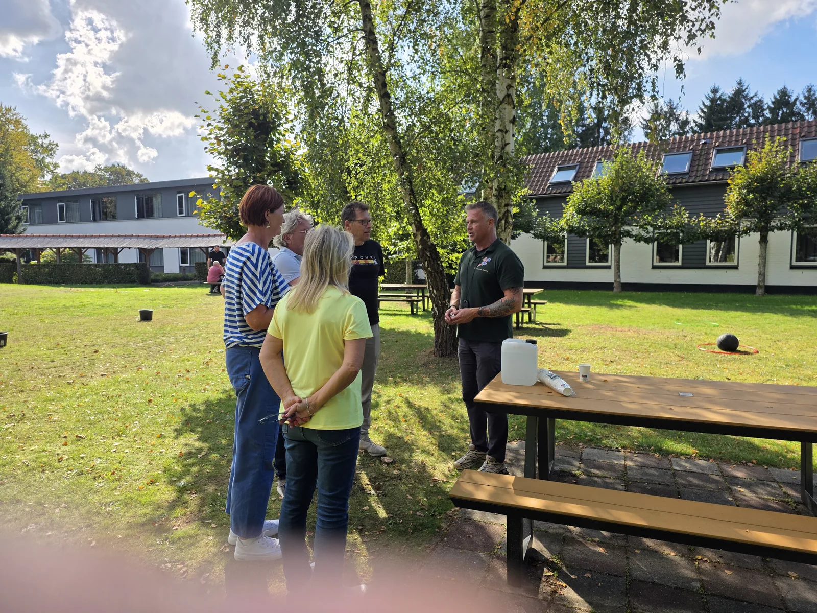 Teamcoaching buiten met een begeleider en deelnemers in gesprek